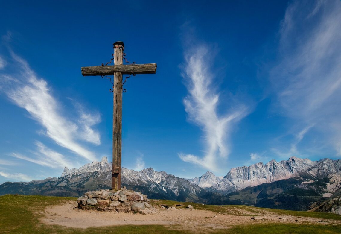 Cross in the mountains, sky with clouds in the backgroun